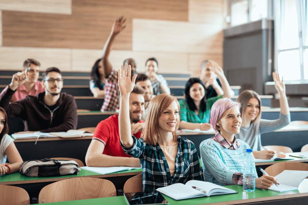 a group of people raising their hands in a classroom