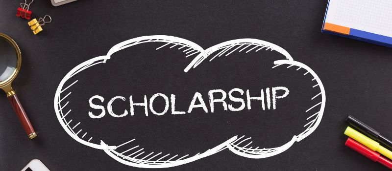 A chalk-drawn speech bubble on a blackboard with the word "SCHOLARSHIP".
