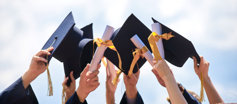 a group of hands holding graduation caps
